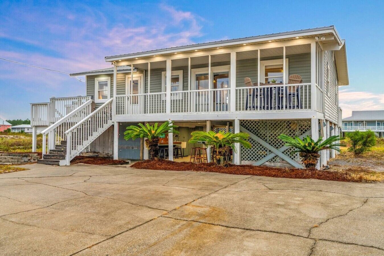 A two-story house with a covered porch, a staircase, and outdoor seating area.