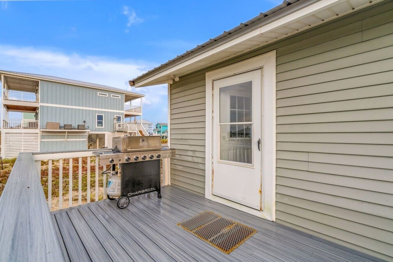 Une terrasse avec un barbecue, une porte et une fenêtre.