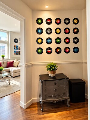 A room with a wall of vinyl records, a dark wooden dresser, and a window with blinds. - Sidemersey Livings - Large, Clean & Cozy Central Loft • Self Check-In (Liverpool)