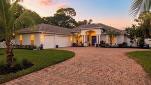 A two-story house with a paved driveway leading to a garage. - A Peaceful Paradise by Avantstay Screened Pool + Outdoor Kitchen + Fire Table 15 Min to 5th Ave (Naples)