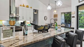 A modern kitchen with a marble countertop, a hammock, and a sign that reads 'welcome sit, relax, enjoy'. - A Peaceful Paradise by Avantstay Screened Pool + Outdoor Kitchen + Fire Table 15 Min to 5th Ave (Naples)