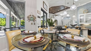 Un espace de salle à manger moderne avec une table en verre pour quatre personnes, entourée de chaises.