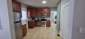 A kitchen with wooden cabinets, stainless steel appliances, and a light wood floor. - Work & Relax / Charming 1BR by GATech & West Midtown & Atlantic Station (Atlanta)