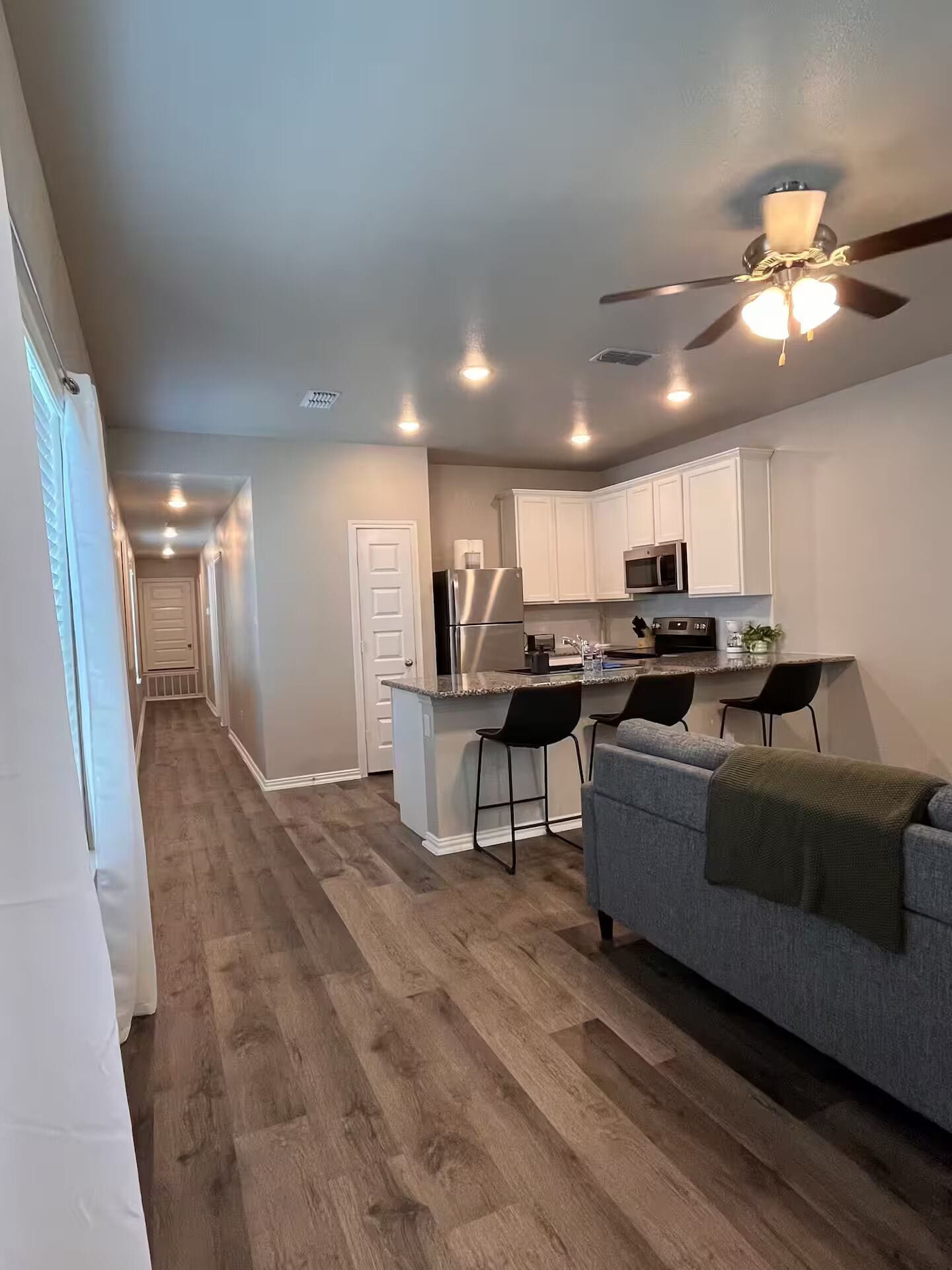 A modern kitchen with white cabinets, a central island, and a ceiling fan.