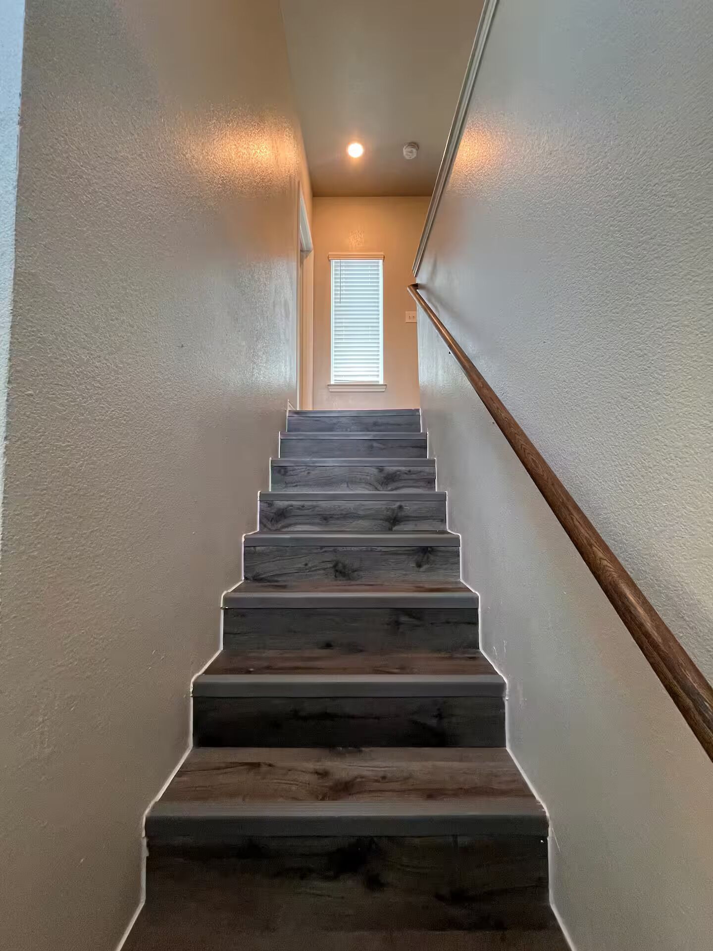 A staircase with wooden steps leading to a landing with a window.