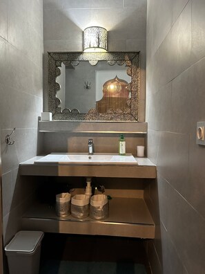 Een badkamer met een wastafel, spiegel en decoratieve verlichting.