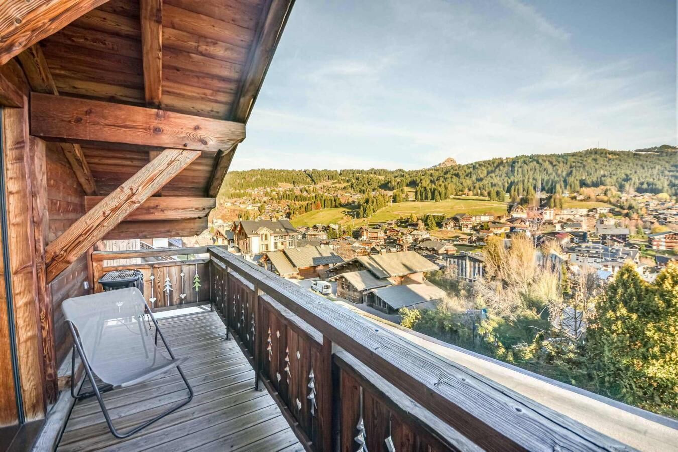 Un balcon en bois offrant une vue sur la ville et les collines.
