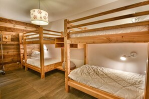 A room with bunk beds, a hanging light fixture, and a wall-mounted clock. - Wifi, 1st floor, view resort, fitness, sauna, balcony, parking, ski locker, 82m², Les Gets (Les Gets)