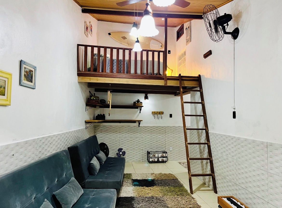 A room with a bunk bed, a sofa, a ladder, and a fan.