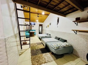 Ein Zimmer mit Hochlaggerl, einer Leitern, einem Fernseher und einer kleinen Küchenzeile.