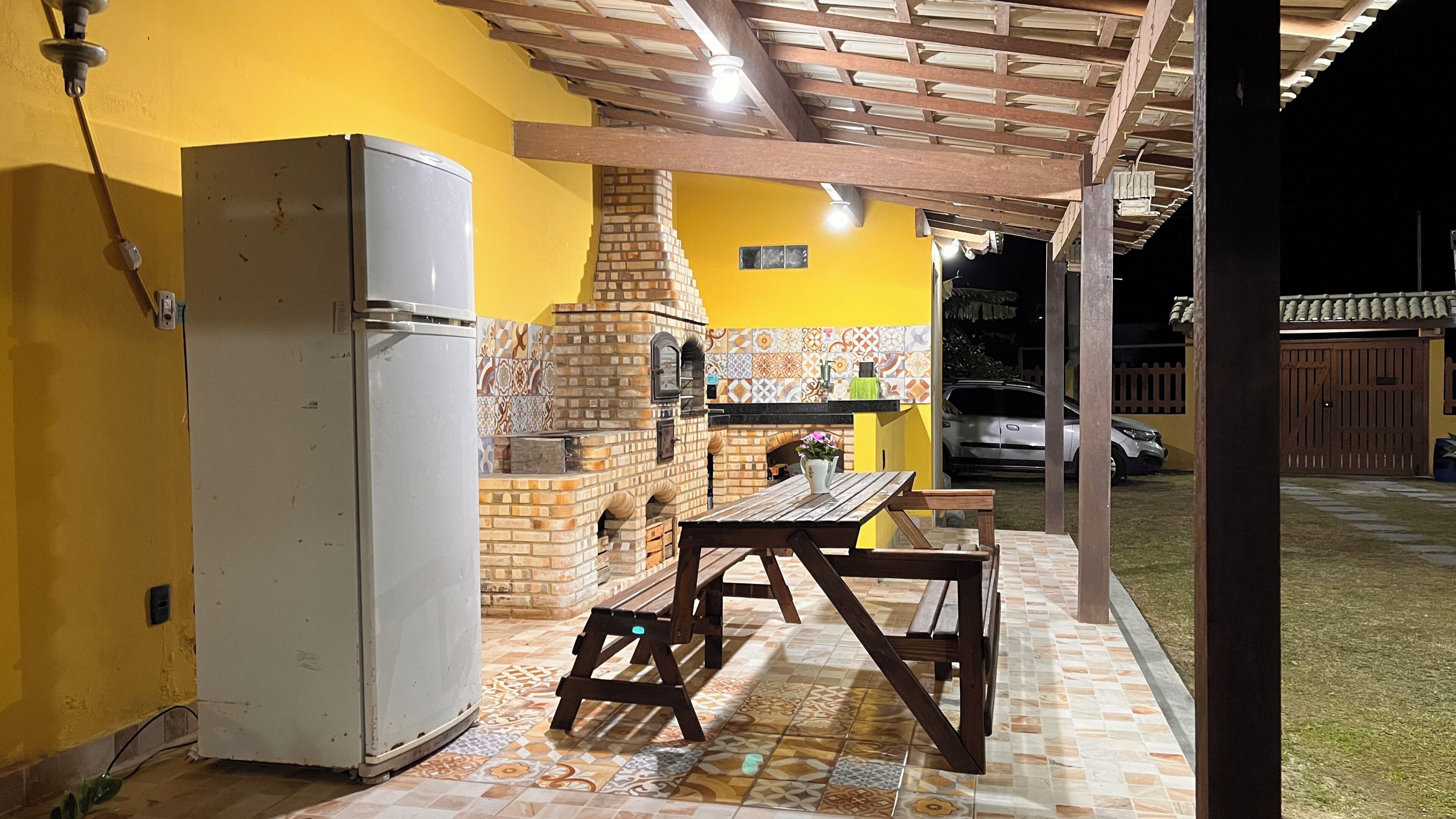 A kitchen with a brick oven, a refrigerator, and a wooden table.