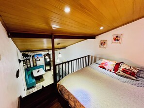 Ein Schlafzimmer mit einem Bett, einem Nachttisch, einem Fenster und Blick auf ein Badezimmer.