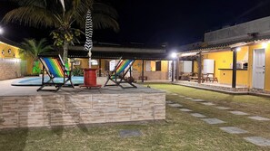 Ein Innenhof mit Pool, Liegestühlen und einer überdachten Sitzgelegenheit.