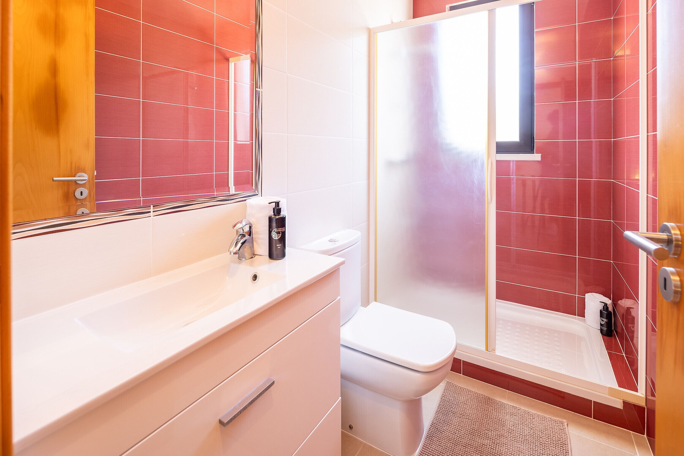 Een badkamer met een wit wastafelmeubel, toilet en douche.
