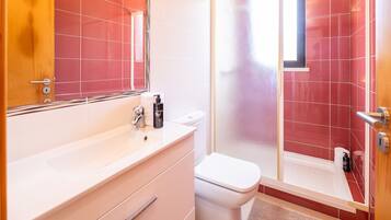 Een badkamer met een wit wastafelmeubel, toilet en douche.