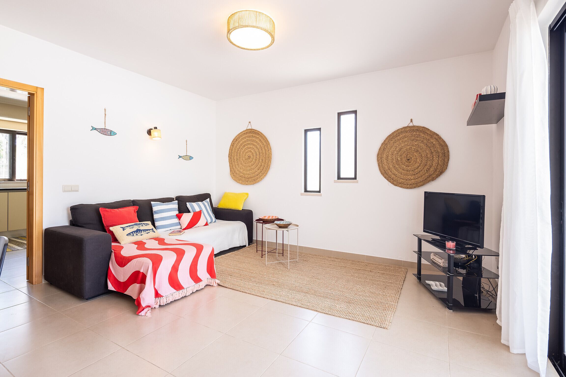 Un salon moderne comprenant un canapé, une table basse, un meuble pour la télévision et des éléments décoratifs fixés au mur.