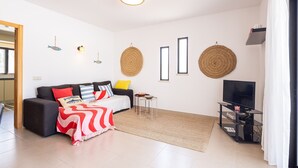 A modern living room with a sofa, a coffee table, a TV stand, and decorative wall hangings. - CAJI- NEW VILLA NEAR THE BEACH (Albufeira)