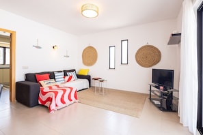 A modern living room with a sofa, a coffee table, a TV stand, and decorative wall hangings. - CAJI- NEW VILLA NEAR THE BEACH (Albufeira)