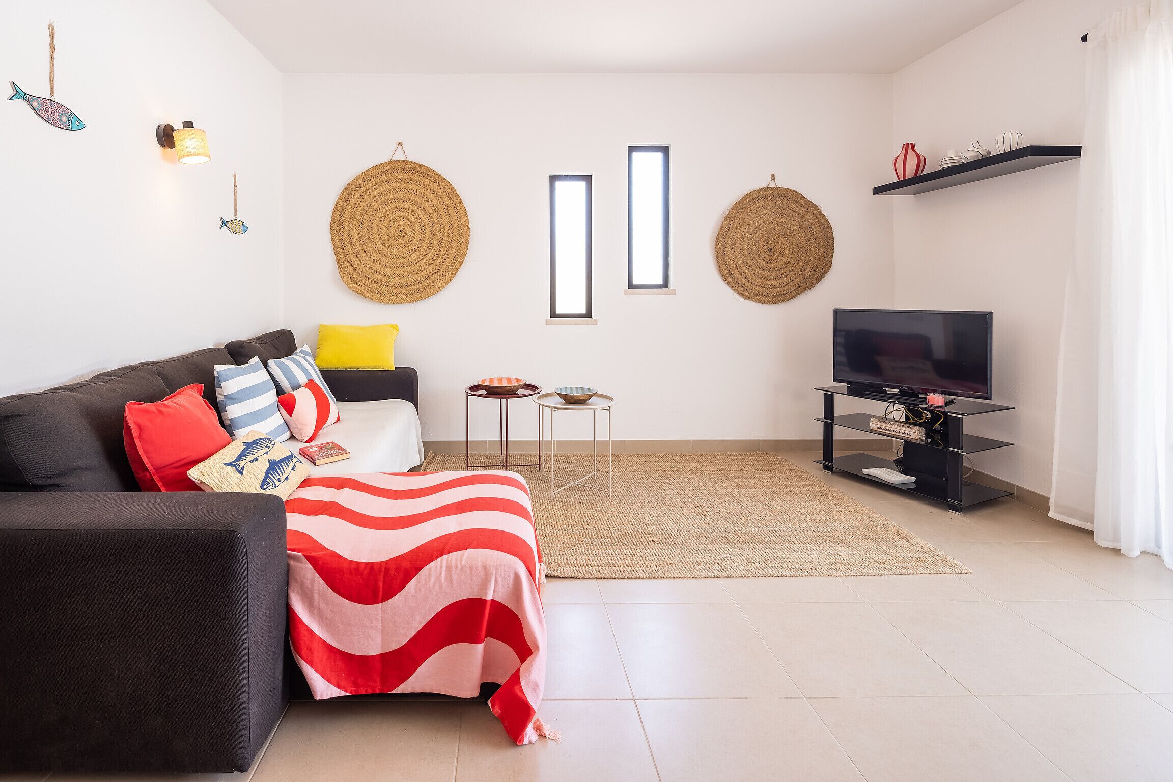 Een moderne woonkamer met een bank, een televisie en decoratieve wanddecoraties.