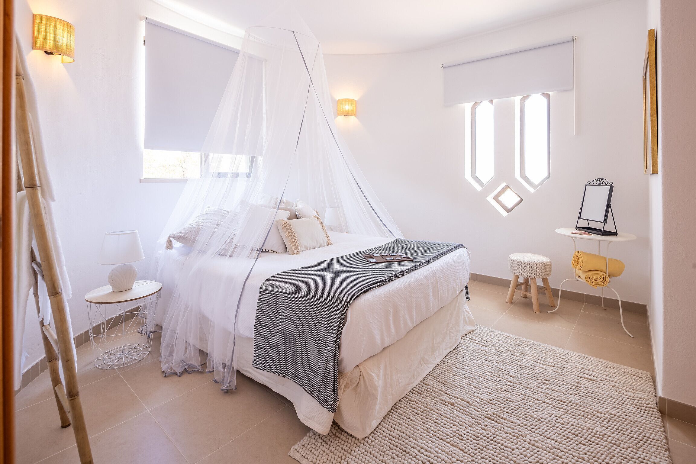 Een slaapkamer met een bed, nachtkastjes, een kaptafel en een raam met uitzicht.