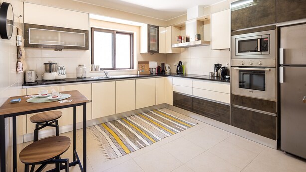 A modern kitchen with a dining area, equipped with a microwave, oven, and coffee maker. - CAJI- NEW VILLA NEAR THE BEACH (Albufeira)