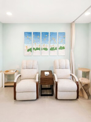 A room with two beige armchairs, a wooden coffee table, and a wall-mounted painting of a landscape. - Gulffront Paradise at Vacation Villa (Fort Myers Beach)