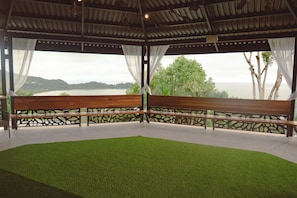 A covered seating area with a bench and a view of a natural landscape.