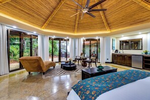 A modern room with a bed, a sofa, a dining table, and a kitchen area.