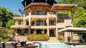 A multi-level house with a pool, outdoor seating, and a covered patio.