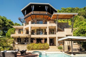 Uma casa com vários níveis, piscina, área de estar externa e varanda coberta.