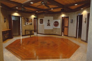 Um quarto espaçoso com piso de madeira, ventiladores de teto e obras de arte nas paredes.