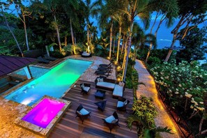 A pool area with a hot tub, lounge chairs, and a deck.