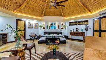A spacious room with a bed, a sofa, a dining table, and a ceiling fan.