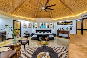A spacious room with a bed, a sofa, a dining table, and a ceiling fan.