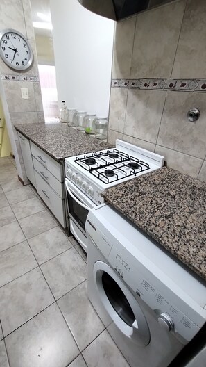 Une cuisine équipée d’une cuisinière à gaz, d’un four et d’un lave-linge encastré.