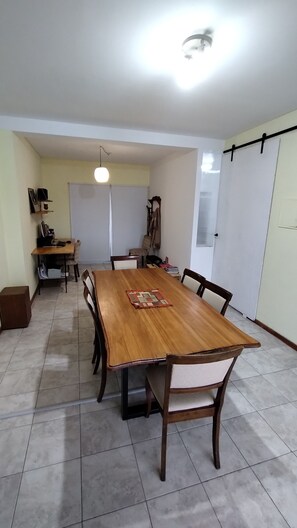 A dining area with a wooden table, chairs, a hanging light fixture, and a whiteboard. - Vrbo Property (San Juan)