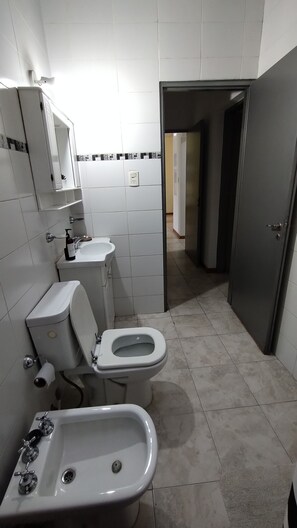 A bathroom with a toilet, bidet, and sink.