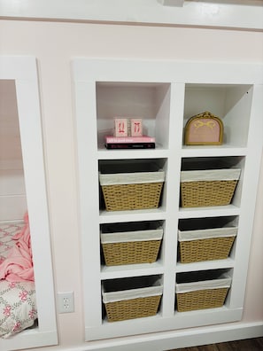A white storage unit with multiple wicker baskets and a framed sign.