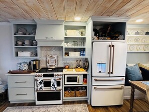 A compact kitchen with a built-in oven, microwave, and a white refrigerator. - Cozy 2-bedroom cottage in beautiful Mentone, AL family friendly modern amenities (Mentone)