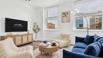 A modern living room with a flat-screen TV, a sofa, a chair, and a coffee table.