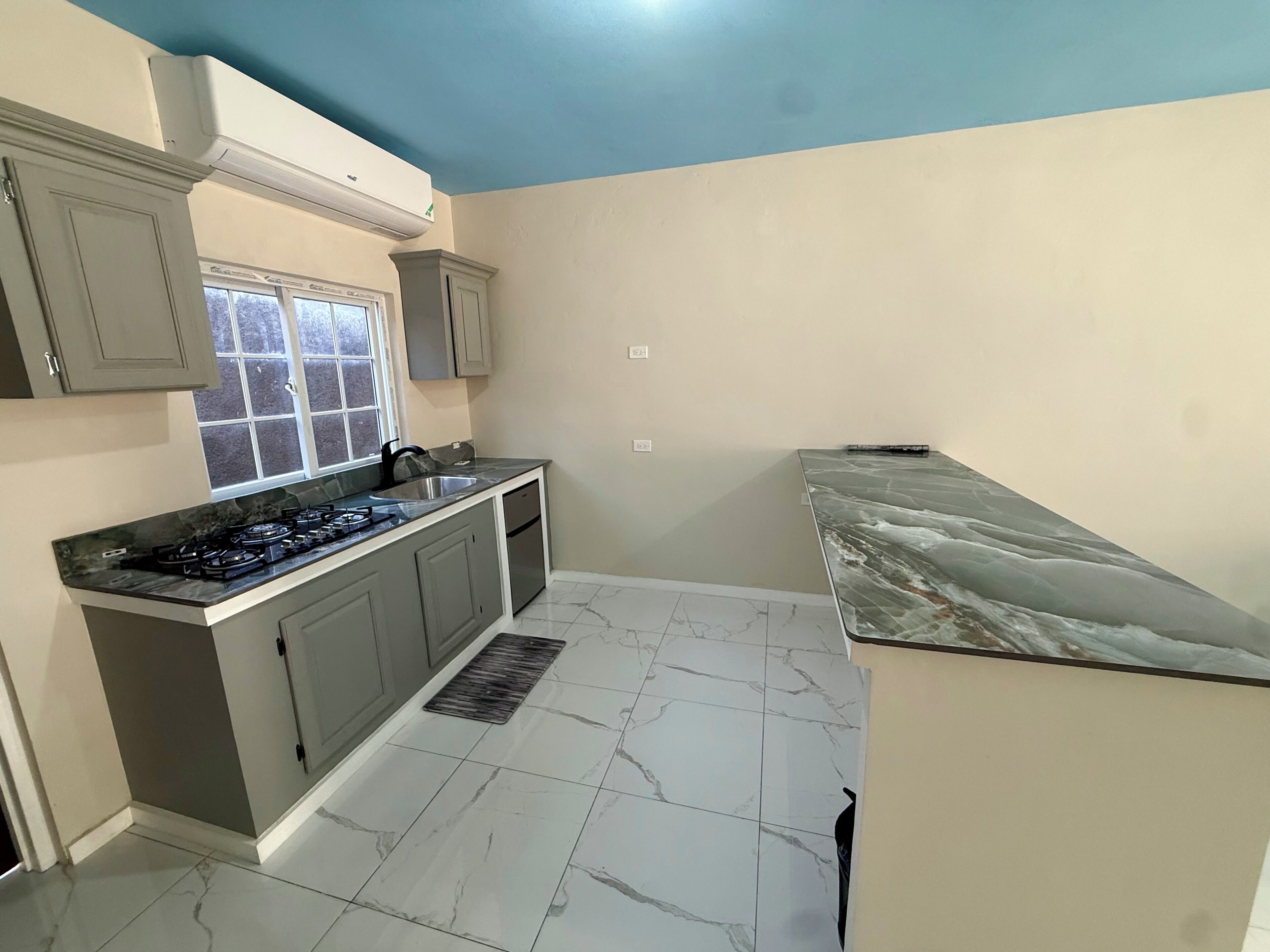 A compact kitchen with a gas stove, a sink, and a window.