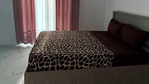 Un dormitorio con cama, cortinas y piso de baldosas.