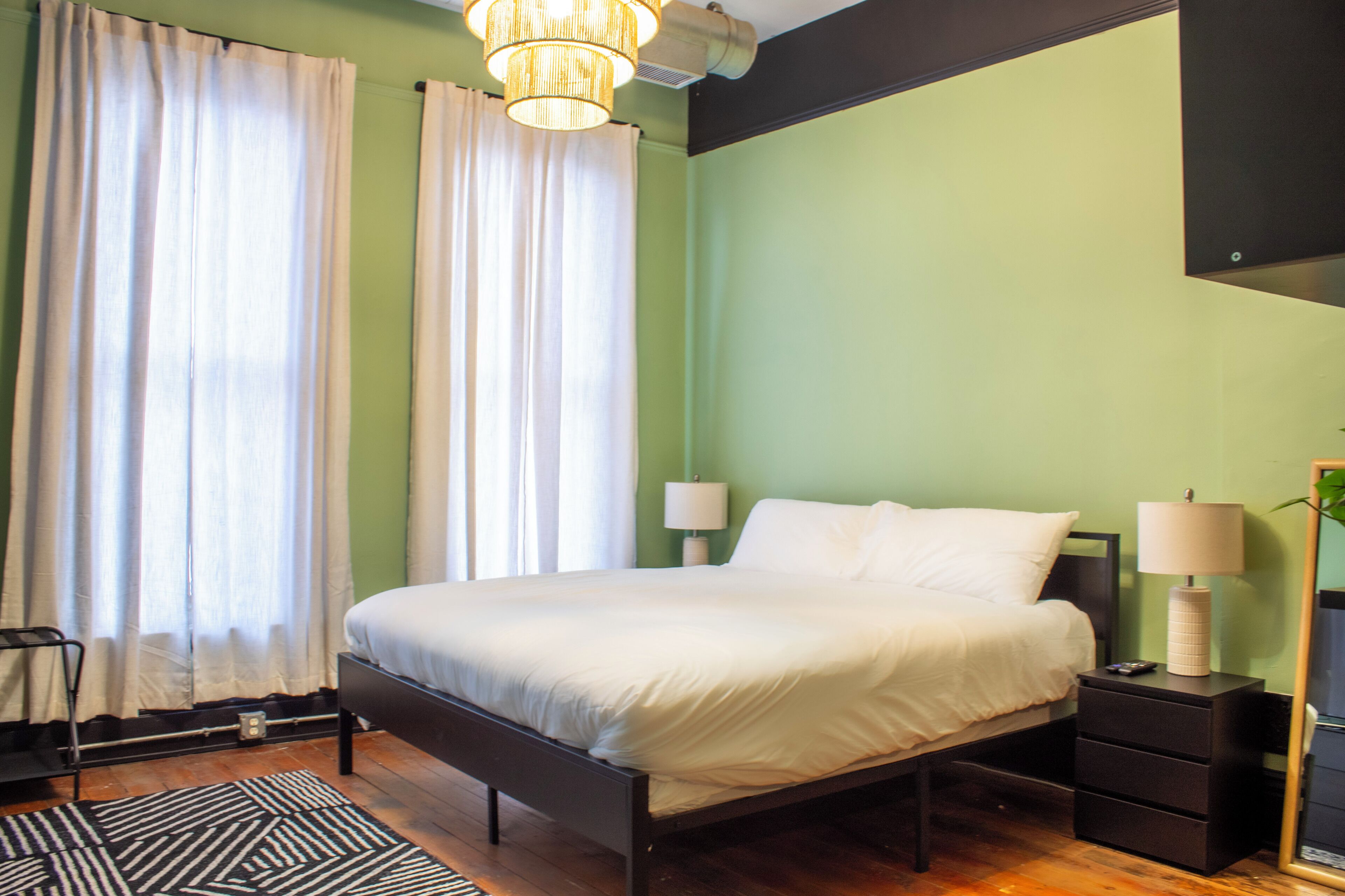 A bedroom with a bed, two bedside lamps, a nightstand, a chair, and a floor lamp.