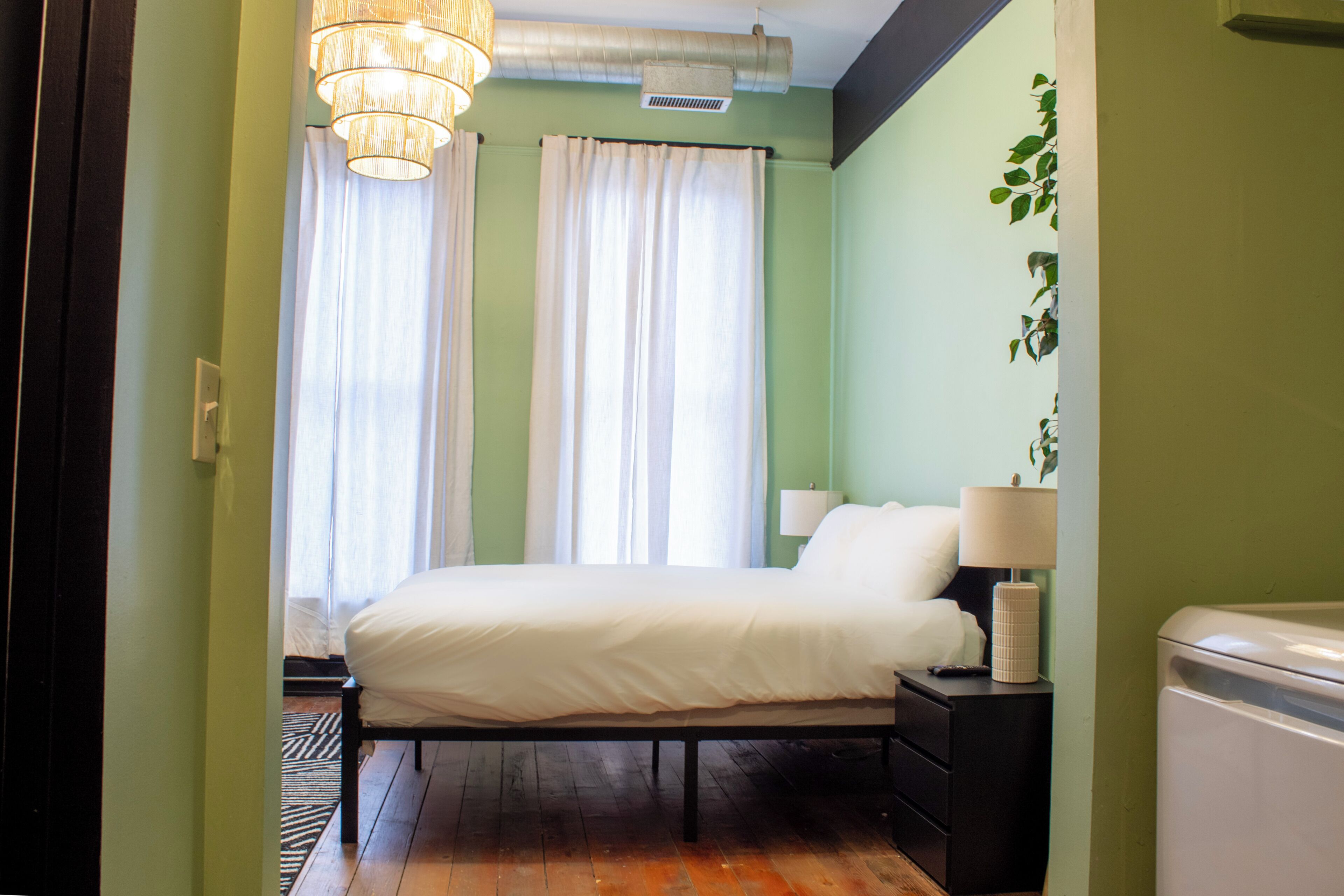 Un dormitorio con cama, mesitas de noche, lámpara y radiador.