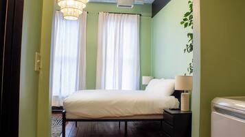 Un dormitorio con cama, mesitas de noche, lámpara y radiador.