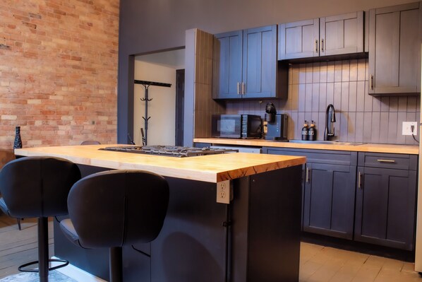 Una cocina moderna con armarios oscuros, una encimera de madera y dos taburetes de bar.