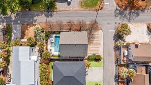 An aerial view of a residential area with a swimming pool, a garage, and a house with a sloped roof. - North Myrtle | Sleeps 14 | Pool & Ping Pong (North Myrtle Beach)