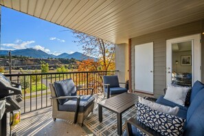 Un balcon agrémenté de meubles en osier, d’une table et offrant une vue sur les montagnes.