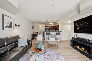 A modern living room with a leather sofa, a glass coffee table, and a fireplace. - The Current | Outside Pool | Hot Tub | Gym | Pets (Invermere)