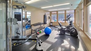 Ein Fitnessraum mit Trainingsgeräten, einem blauen Gymnastikball und einem stationären Fahrrad.
